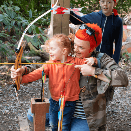 Young girl and mum doing archery together in the forest with young boy smiling behind them