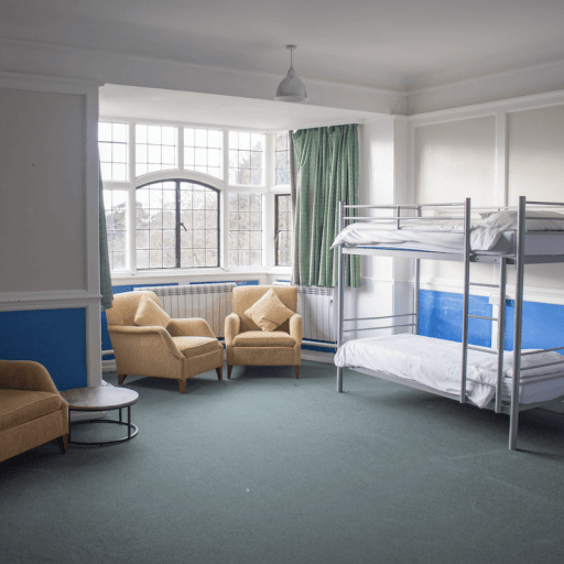 accommodation in the main house at avon tyrrell - two bunk beds wth single beds and three arm chairs infront of large window