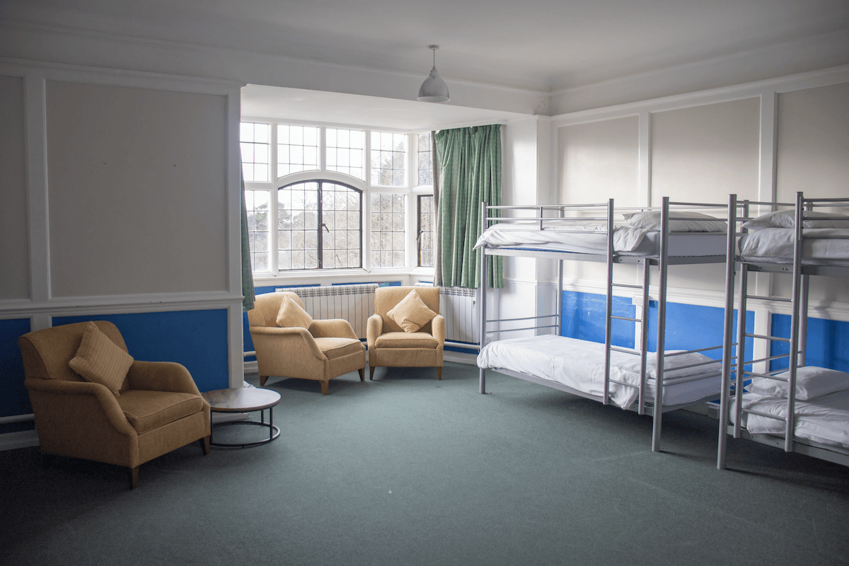 accommodation in the main house at avon tyrrell - two bunk beds wth single beds and three arm chairs infront of large window