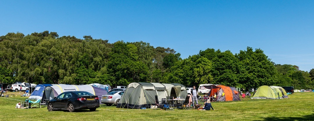 Camping fieild at lakeside camping at avon tyrrell full of families camping in their tents with cars on their pitches