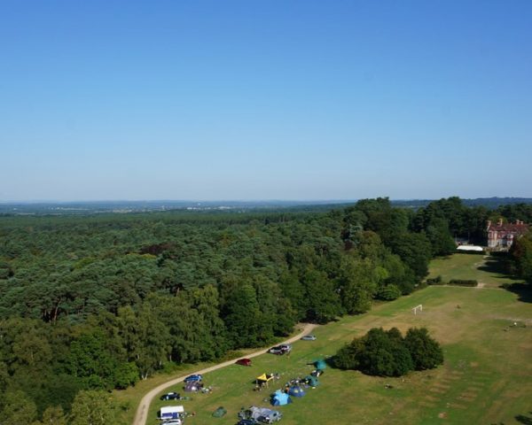 Aerial image shot on a drone of Avon Tyrrell's manor house in the New Forest - the manor house sits on a large forest site with trees and grass areas surronding it with tents out for campers