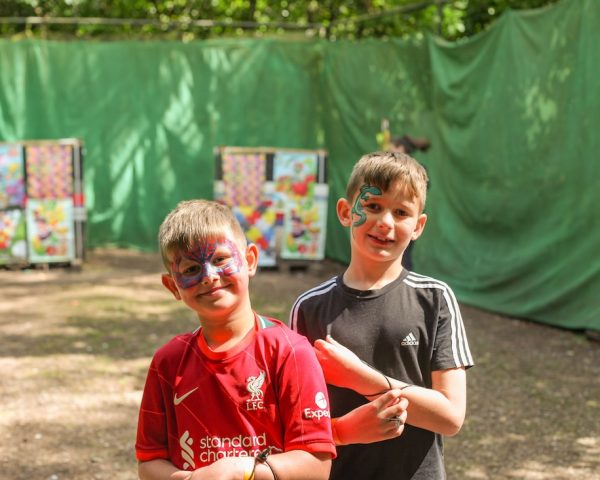 two boys with face paint stood in front of archery targets in the forest