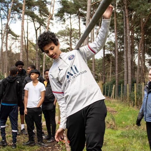 Group of young people with one boy balancing across a walkway
