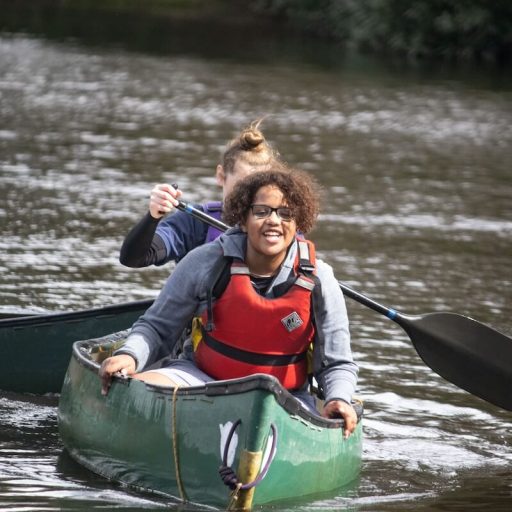 Young person in kayak smiling on a lake in the new forest at avon tyrell