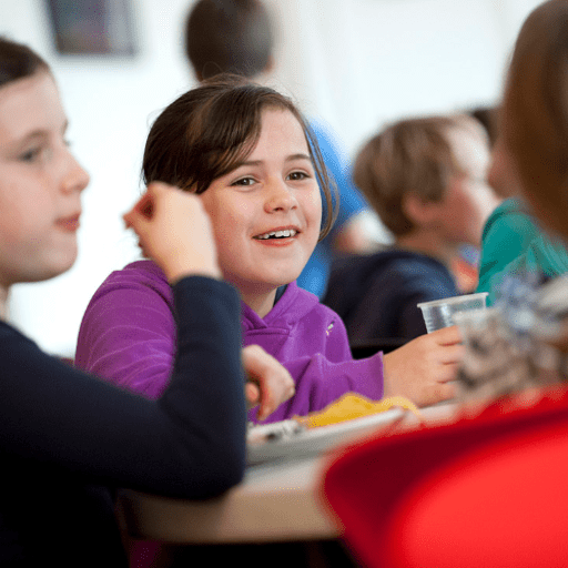Young girls sat in the dining room at avon tyrell smiling whilst eating