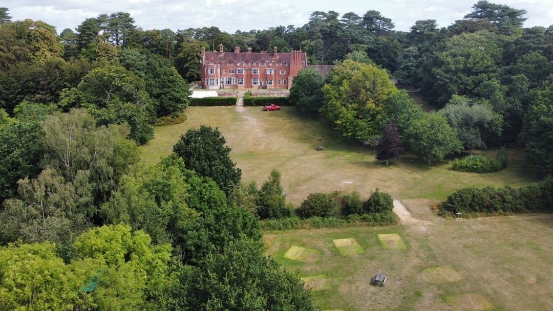 Aerial image shot on a drone of Avon Tyrrell's manor house in the New Forest - the manor house sits on a large forest site with trees and grass areas surronding it