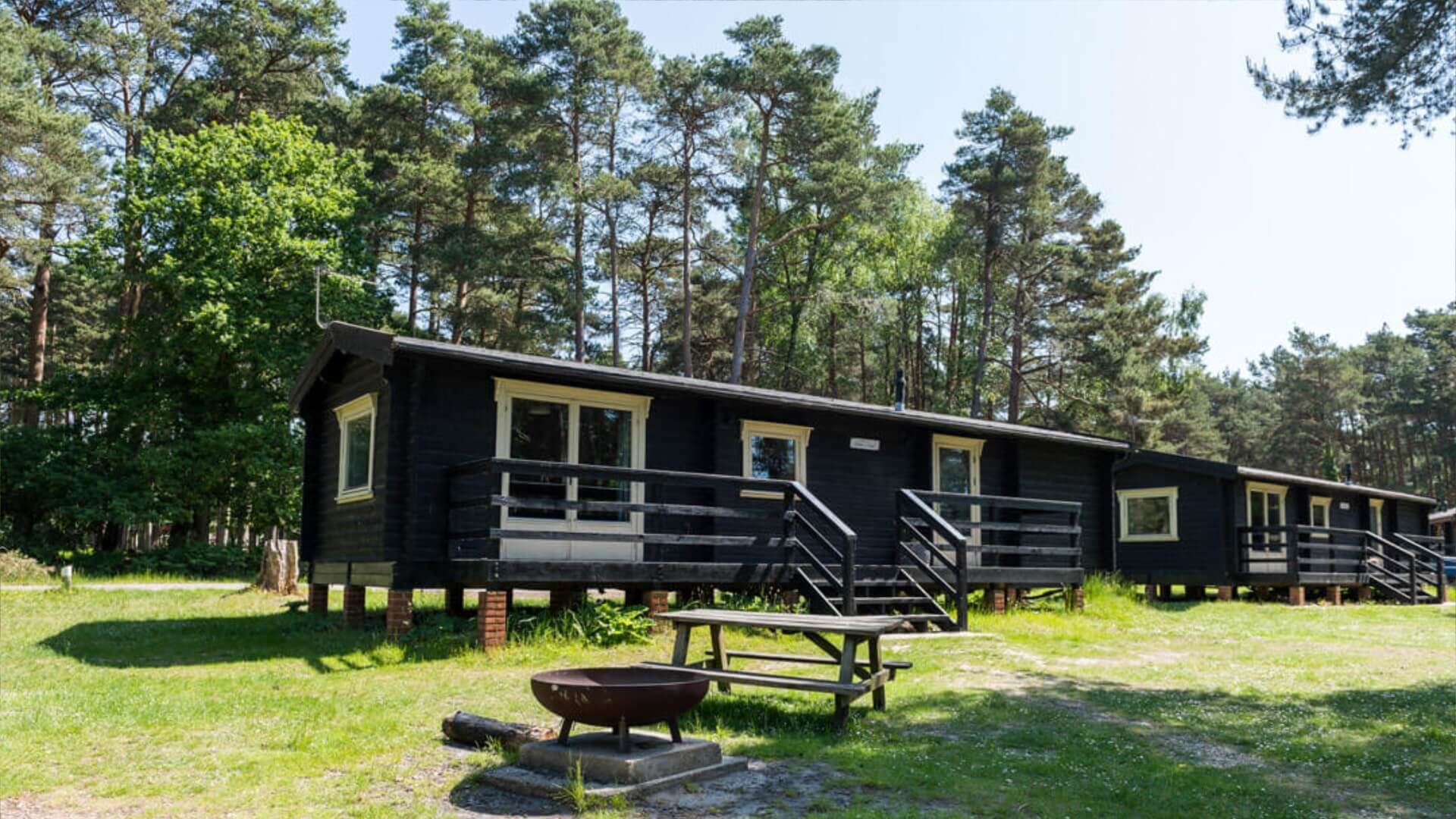 Lodge in the new forest at avon tyrrell with trees and nature - picnic bench and fire pit infront of lodge