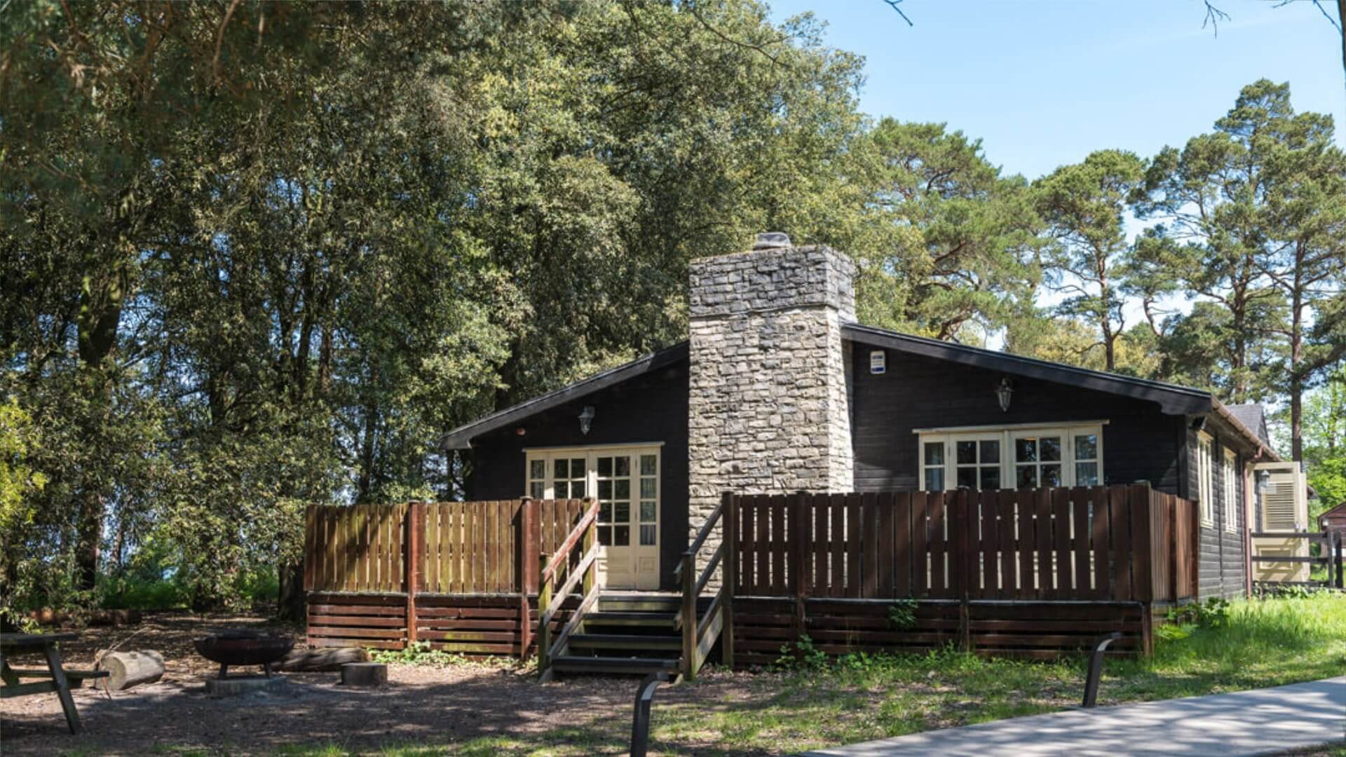 Avon Tyrrell forest lodge with a chimney and balcony
