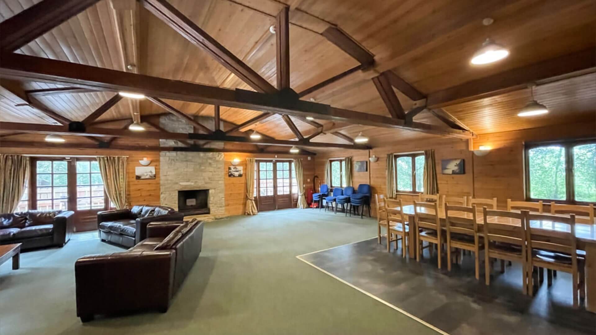 Inside a large lodge at avon tyrrell in the forest - leather sofa chill area with a large wooden dining table and chairs