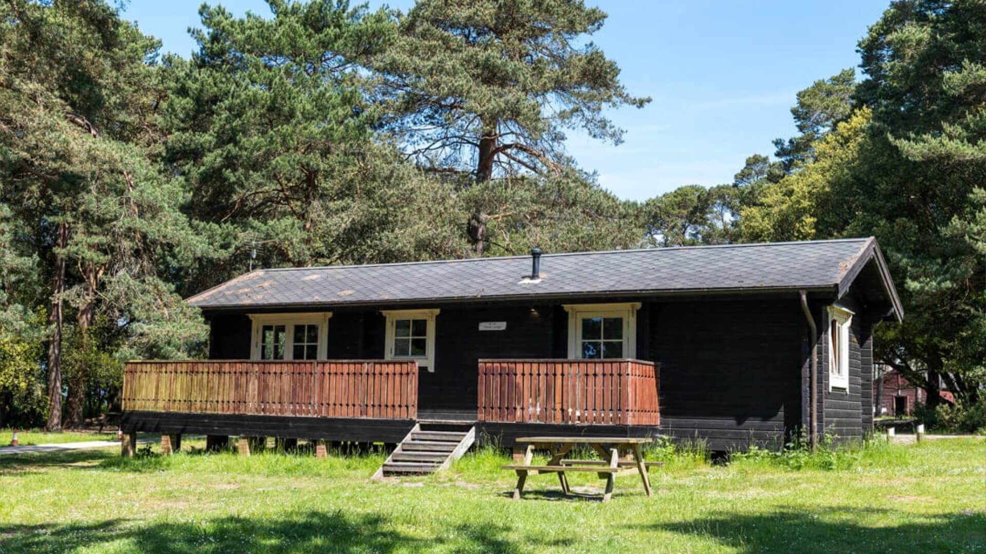 Lodge in the new forest at avon tyrrell with trees and nature - picnic bench infront of lodge