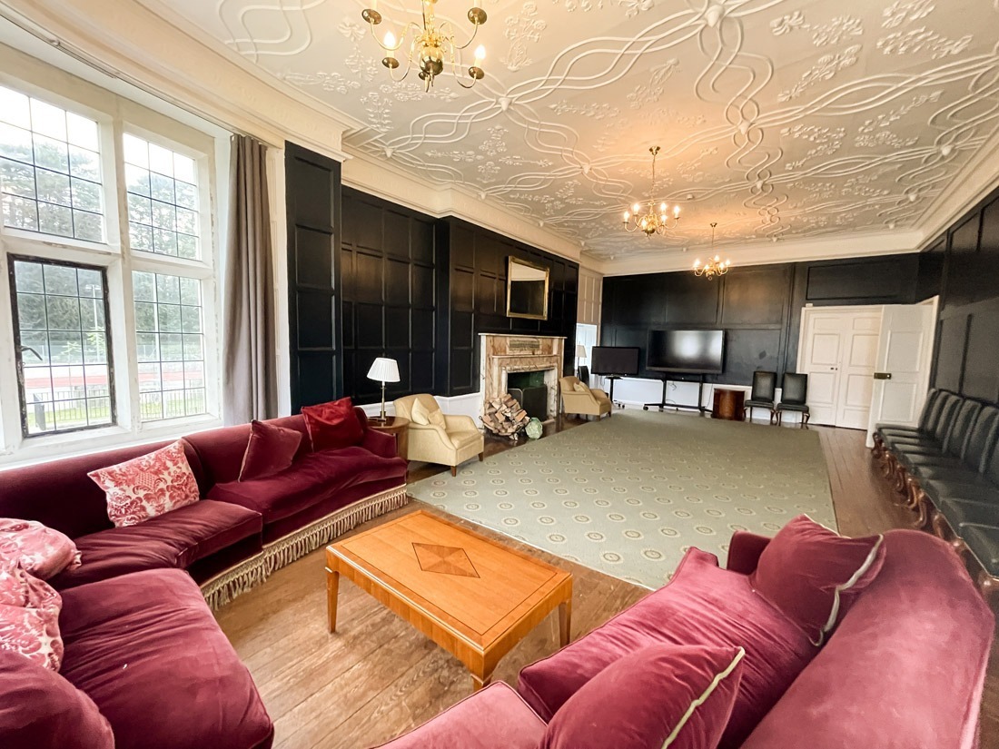 Avon Tyrrell's manor house drawing room for guests with comfy sofa, chairs, open fire and TV