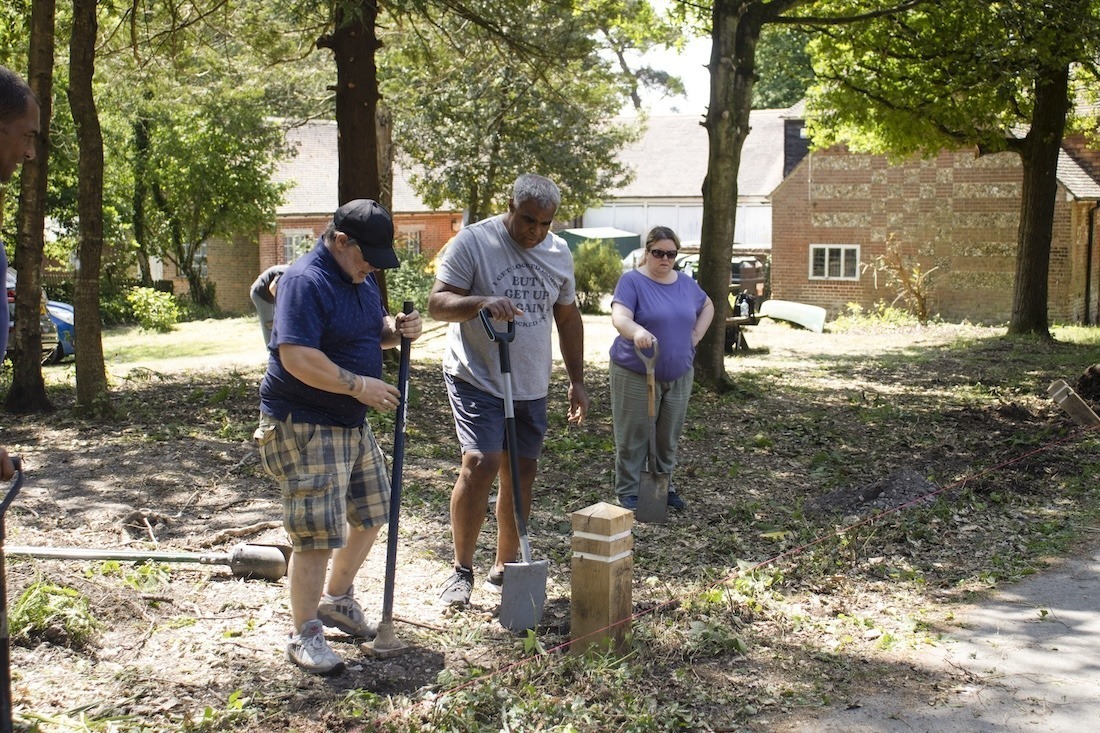 Two adults doing some volunteering gardening working on a wooden fence in the forest at avon tyrrell