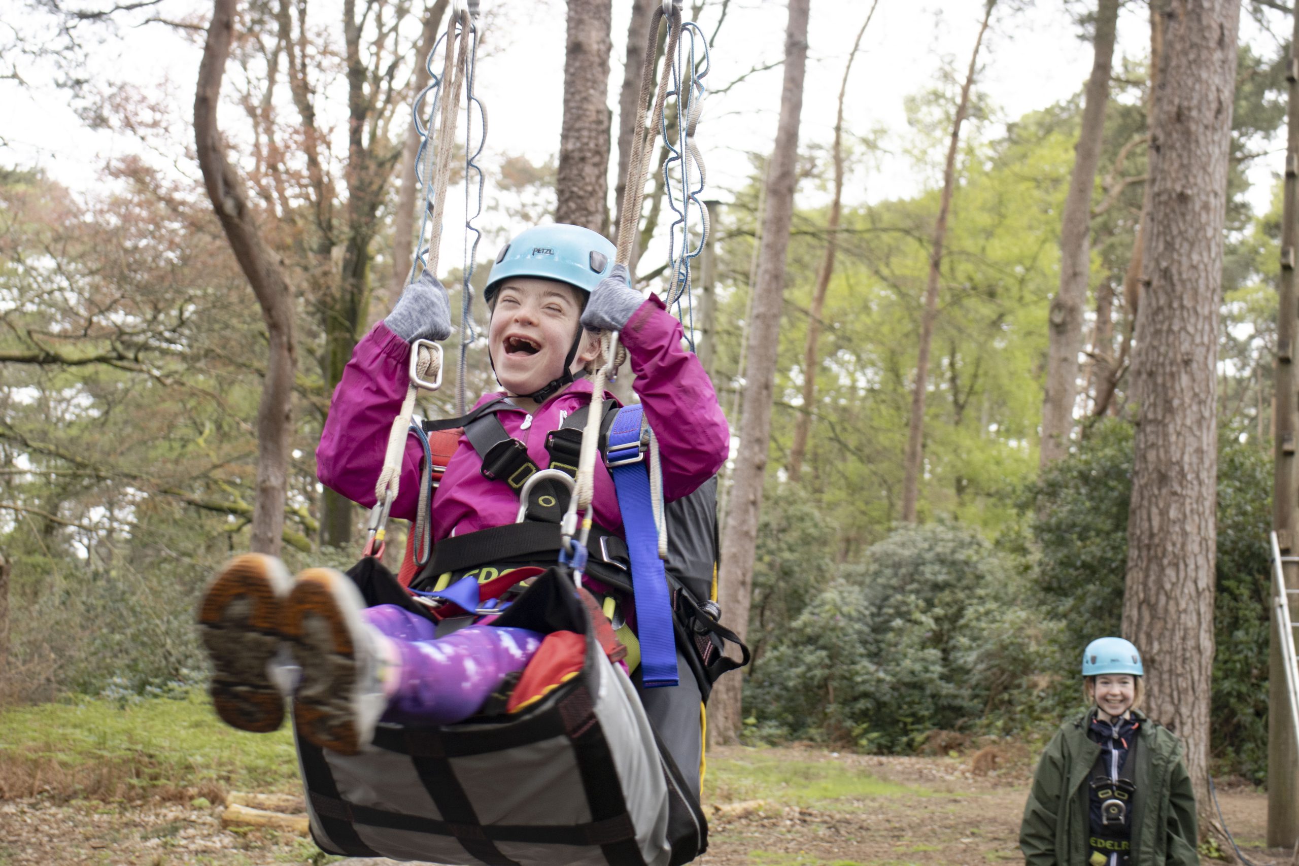 SEND young person on specialised harness doing high ropes smiling