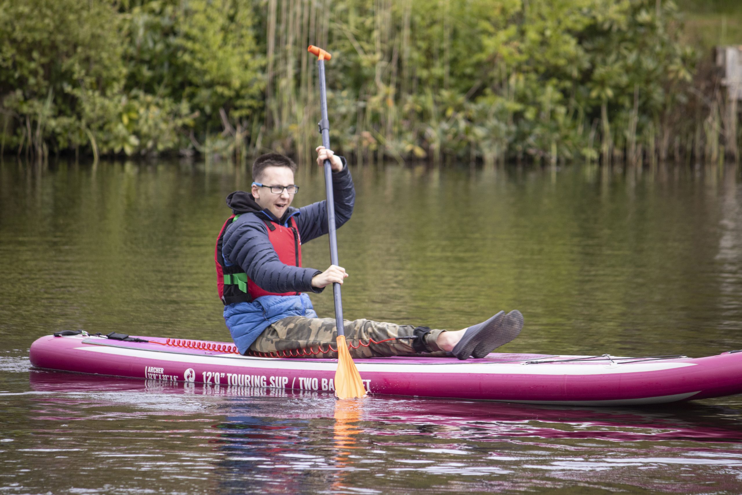 young person on paddle board on Avon tyrrells take in the new forest
