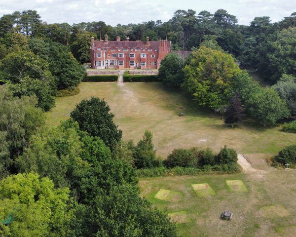 Avon Tyrrell Manor House in the New Forest National Park with trees and grass surrounding building drone image