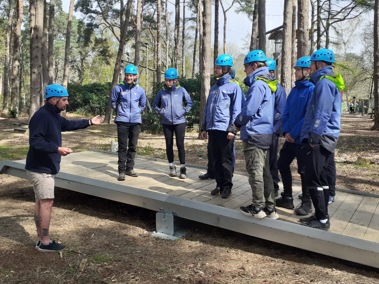 apprentices at Avon Tyrrell in the New Forest under trees doing low ropes training