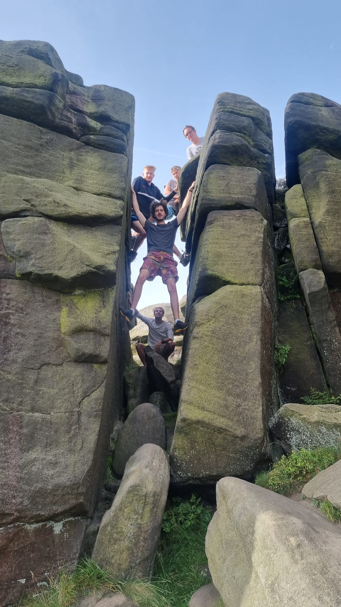 apprentices smiling to camera in the peak district surrounded by big boulders