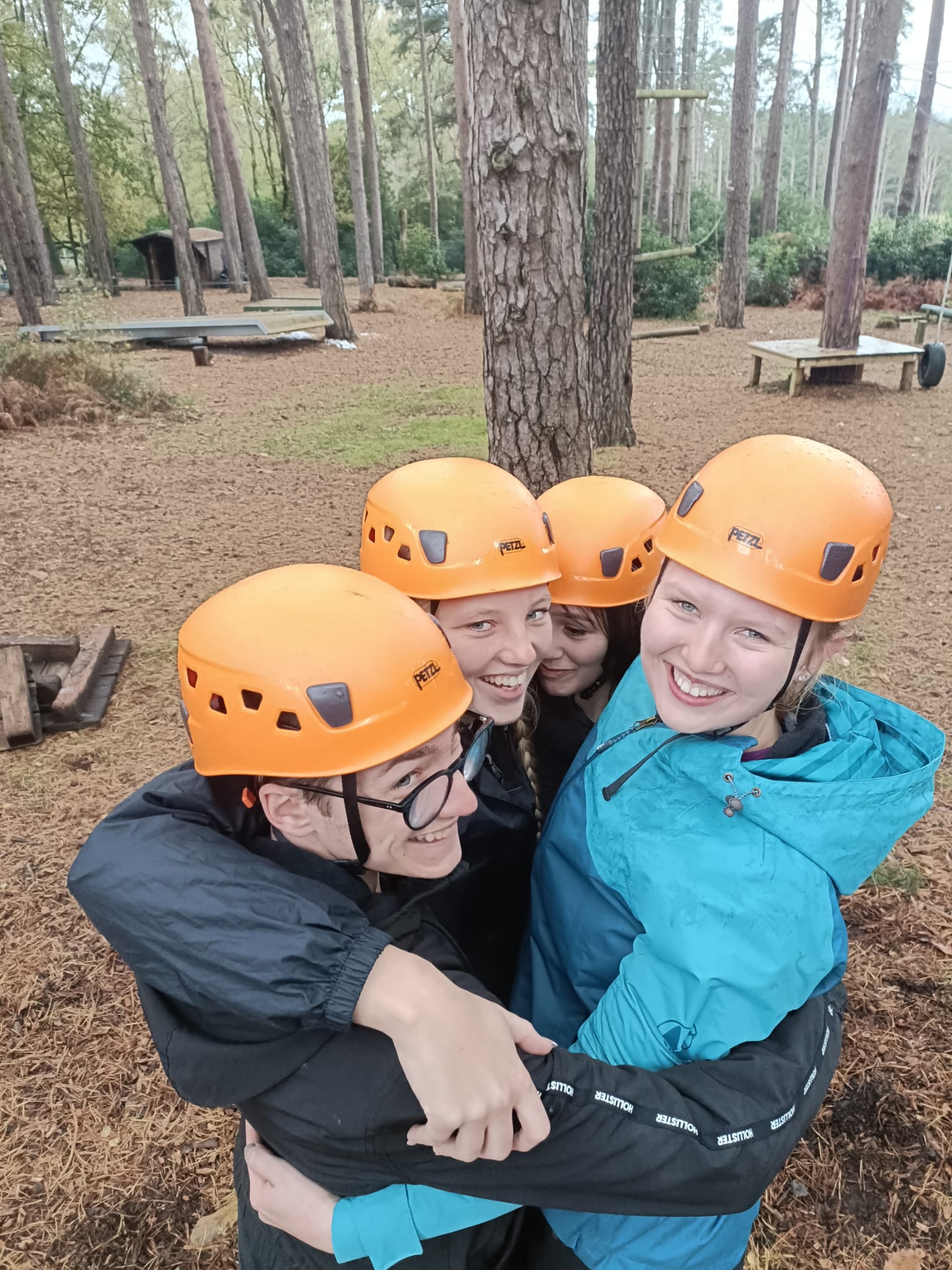 apprentices all smiling and hugging wearing helmets whilst doing a low ropes course in the forest