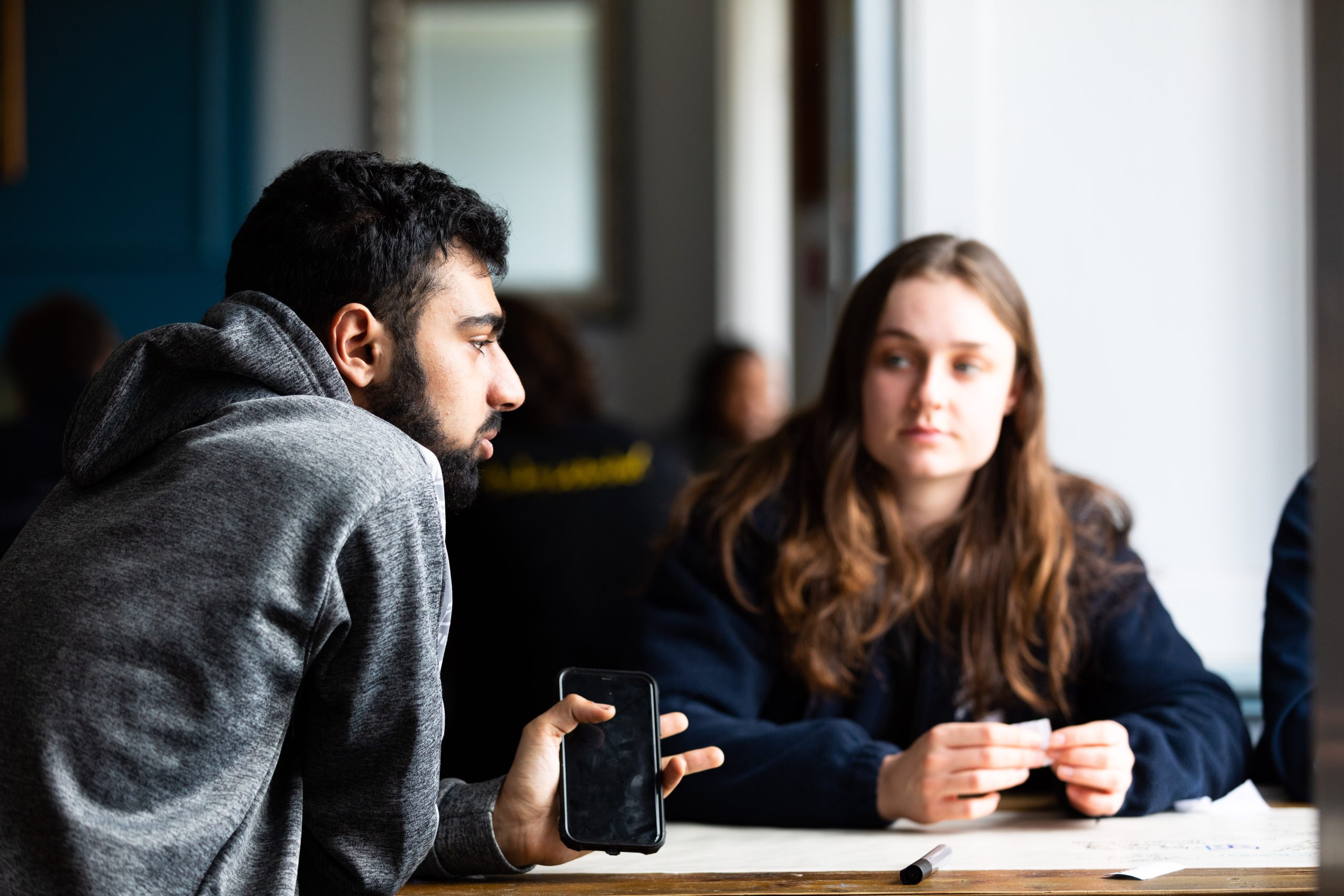 two people sat at table looking and talking to each other